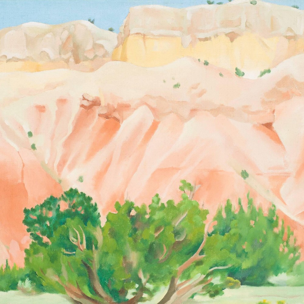 Georgia O'Keeffe's My Back Yard (1943): layered desert cliffs in peach, apricot and yellow above green cedar trees, beneath a narrow band of flat blue sky.