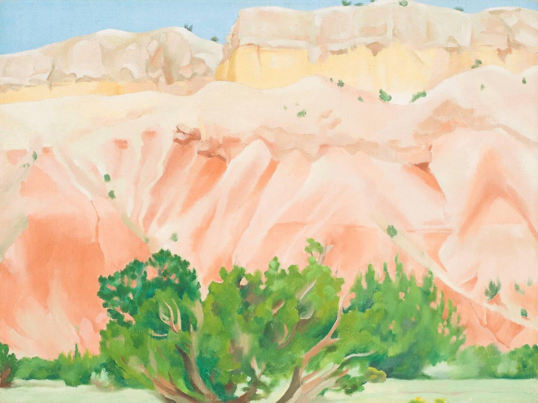 Georgia O'Keeffe's My Back Yard (1943): layered desert cliffs in peach, apricot and yellow above green cedar trees, beneath a narrow band of flat blue sky.