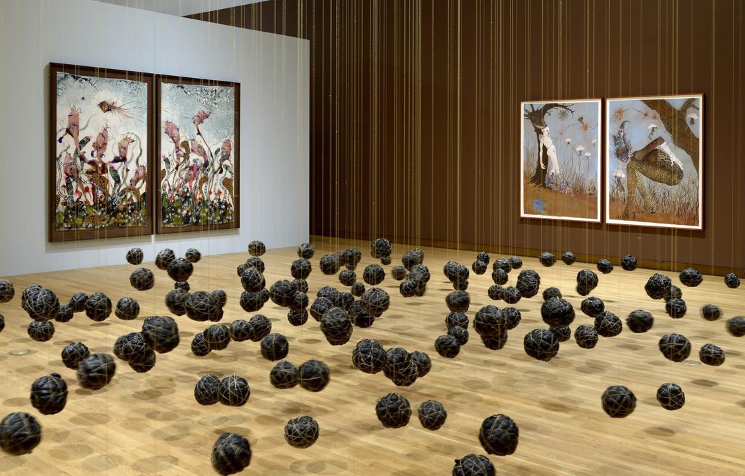 Installation view of Wangechi Mutu’s A Fantastic Journey at the Nasher Museum, showing large-scale collages on the walls and a suspended installation of dark spheres.