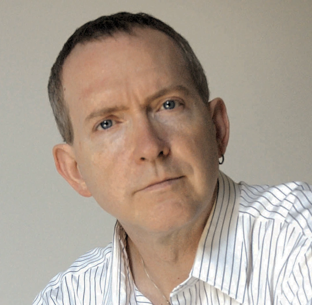 Portrait of Kenn Day, a man with blue eyes in a striped shirt, on his website.