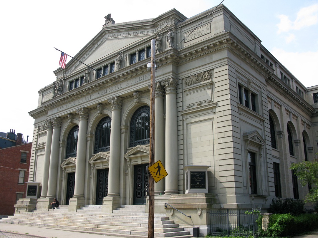 The neoclassical stone facade of Memorial Hall in Over-the-Rhine, Cincinnati, with columns, arched windows and a broad front staircase.