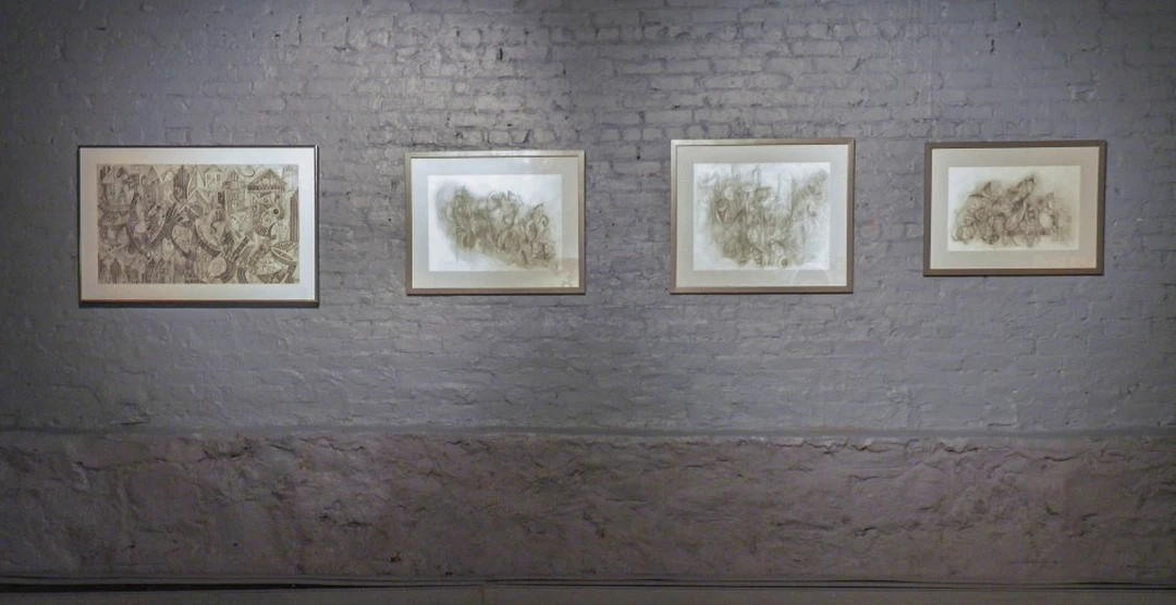 Four framed abstract drawings in a row on a white brick gallery wall. Photograph by Cedric Cox.