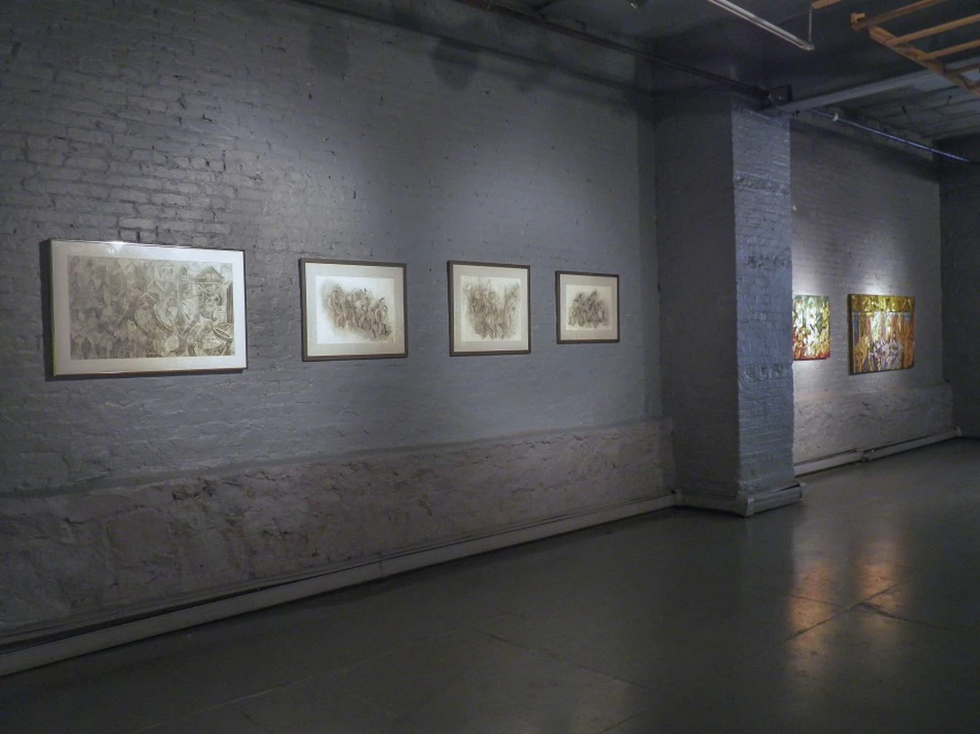 Four framed abstract drawings on a white brick gallery wall, with two colorful paintings visible around a corner. Photograph by Cedric Cox.