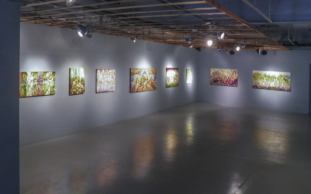 Corner view of a gallery with eight colorful abstract paintings under track lighting. Photograph by Cedric Cox.