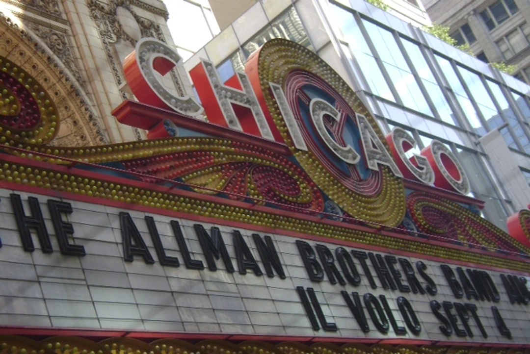 The Chicago Theatre at night: the tall illuminated vertical sign reading CHICAGO in red and white letters above the marquee announcing THE ALLMAN BROTHERS BAND and IL VOLO SEPT 4.