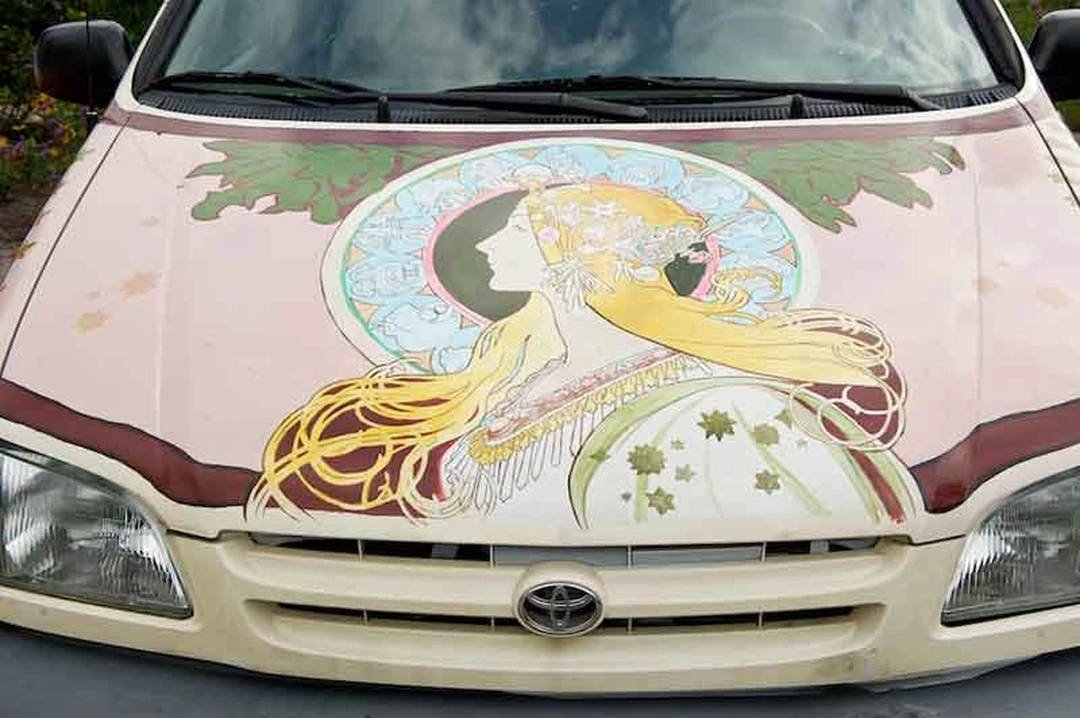 Car hood painted with a Mucha-style profile of a woman with flowing blond hair.