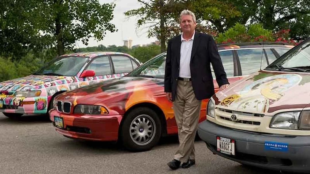 Kip Eagen standing between three painted art cars.