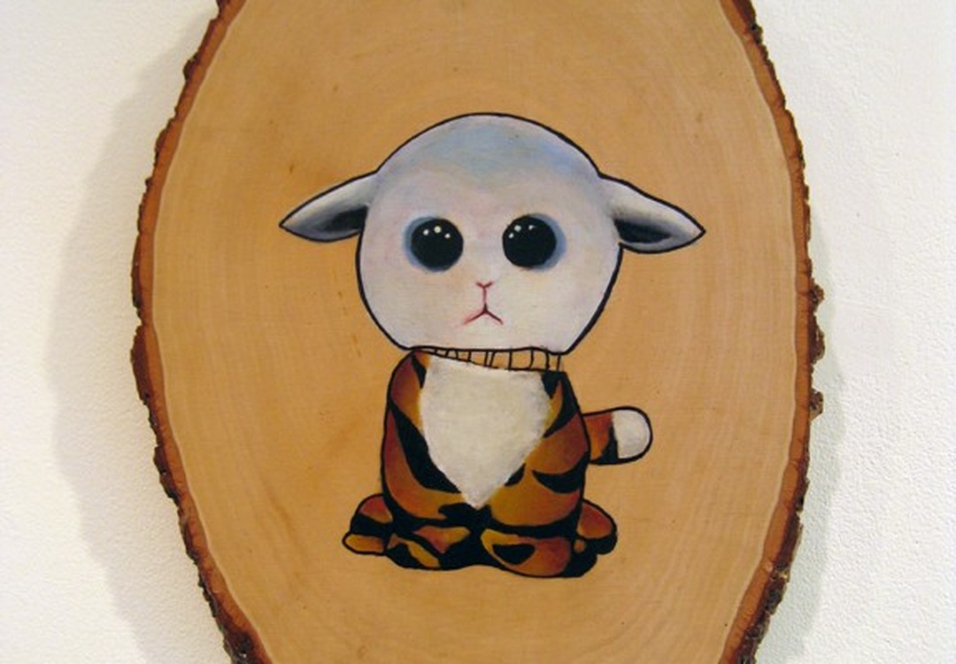 Painting of a lamb's head on a tiger-striped body, on a wood slice