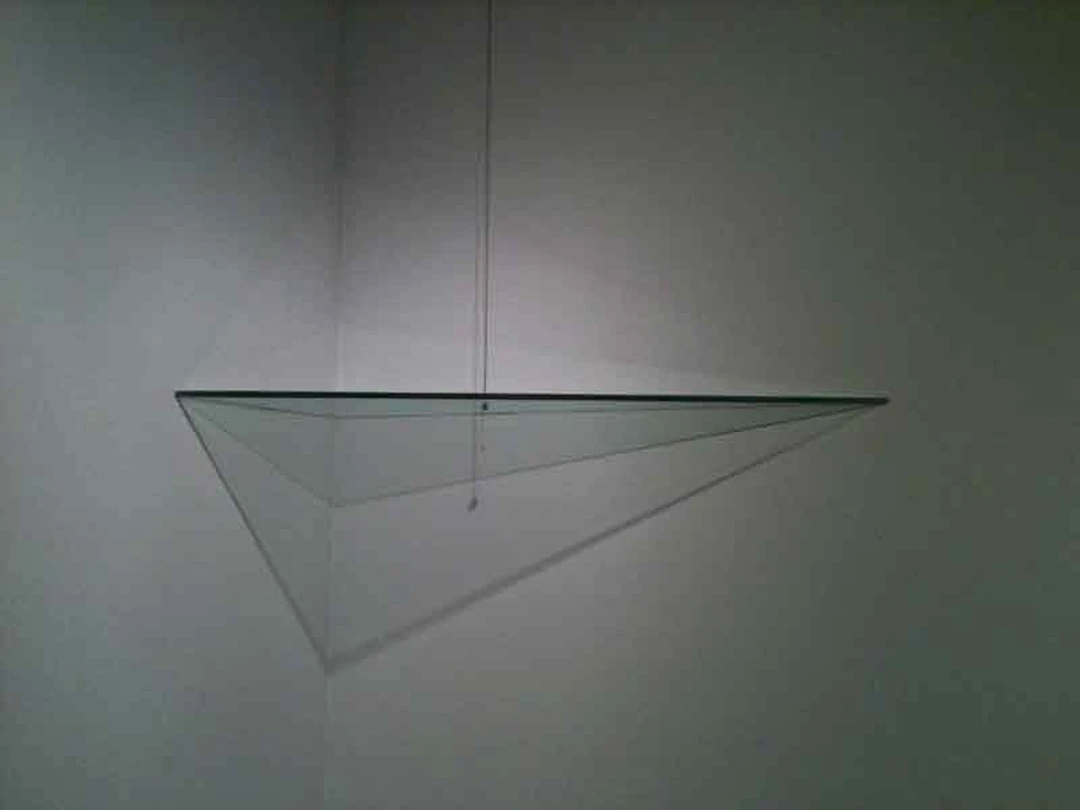 Glass Brick, a triangular glass sculpture installed in a gallery corner.