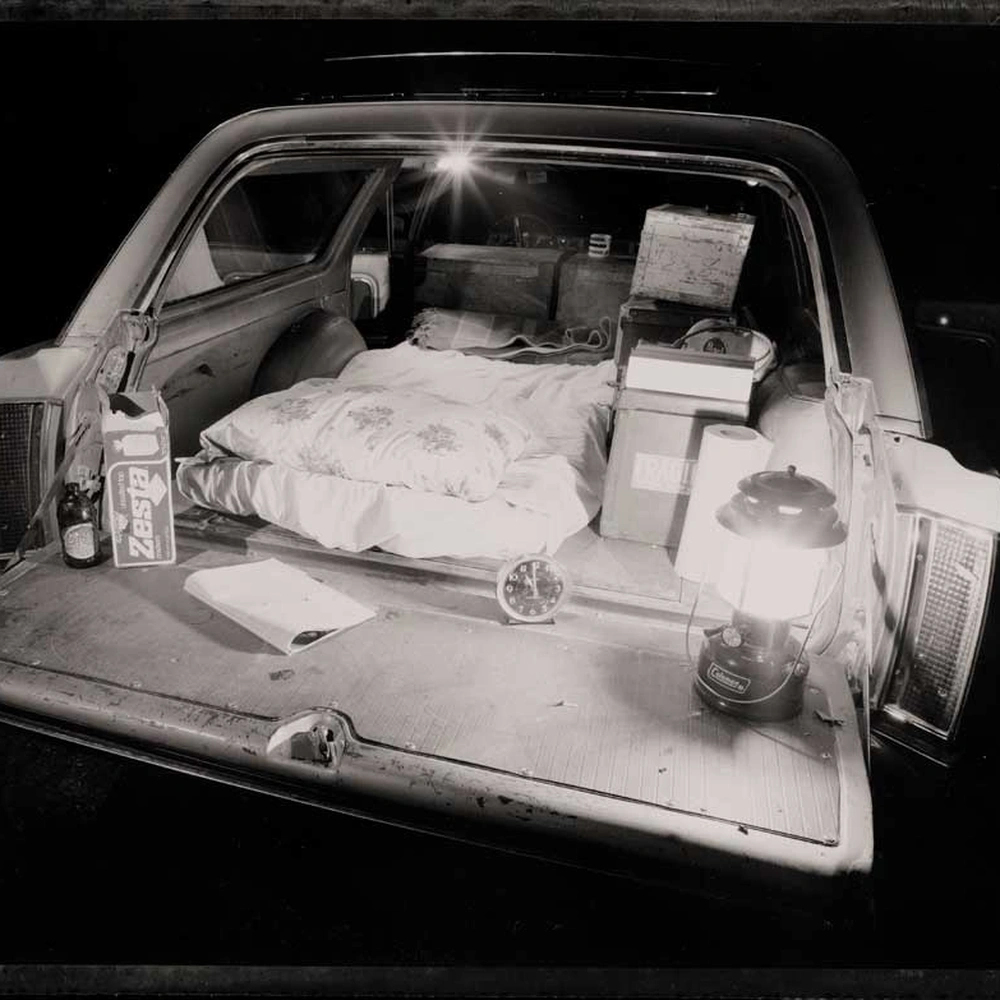 Bob Hower, My bed, in the back of my 1965 Vista Cruiser: a mattress, lantern, clock and boxes in the open tailgate of a station wagon at night.
