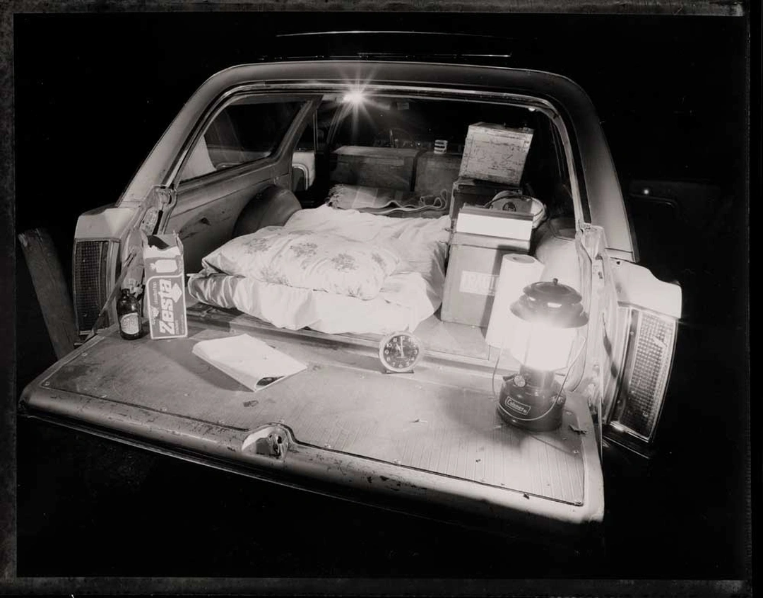 Bob Hower, My bed, in the back of my 1965 Vista Cruiser: a mattress, lantern, clock and boxes in the open tailgate of a station wagon at night.