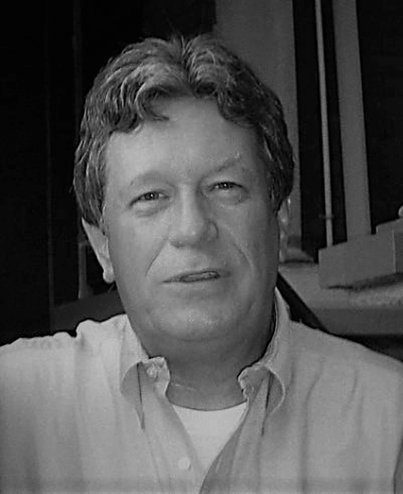 Black-and-white portrait photograph of the poet James Cummins, graying hair, wearing a light-colored collared shirt.