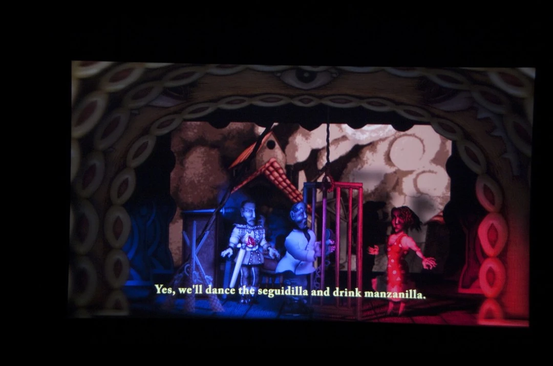 Jay Bolotin, Kharmen, 2013, digital video (film still): puppet characters on a stage with the subtitle “Yes, we’ll dance the seguidilla and drink manzanilla.”