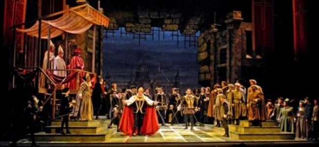 Crowd scene on a stone stage: a cardinal in a red cape at center, a bishop on a raised platform, courtiers around.