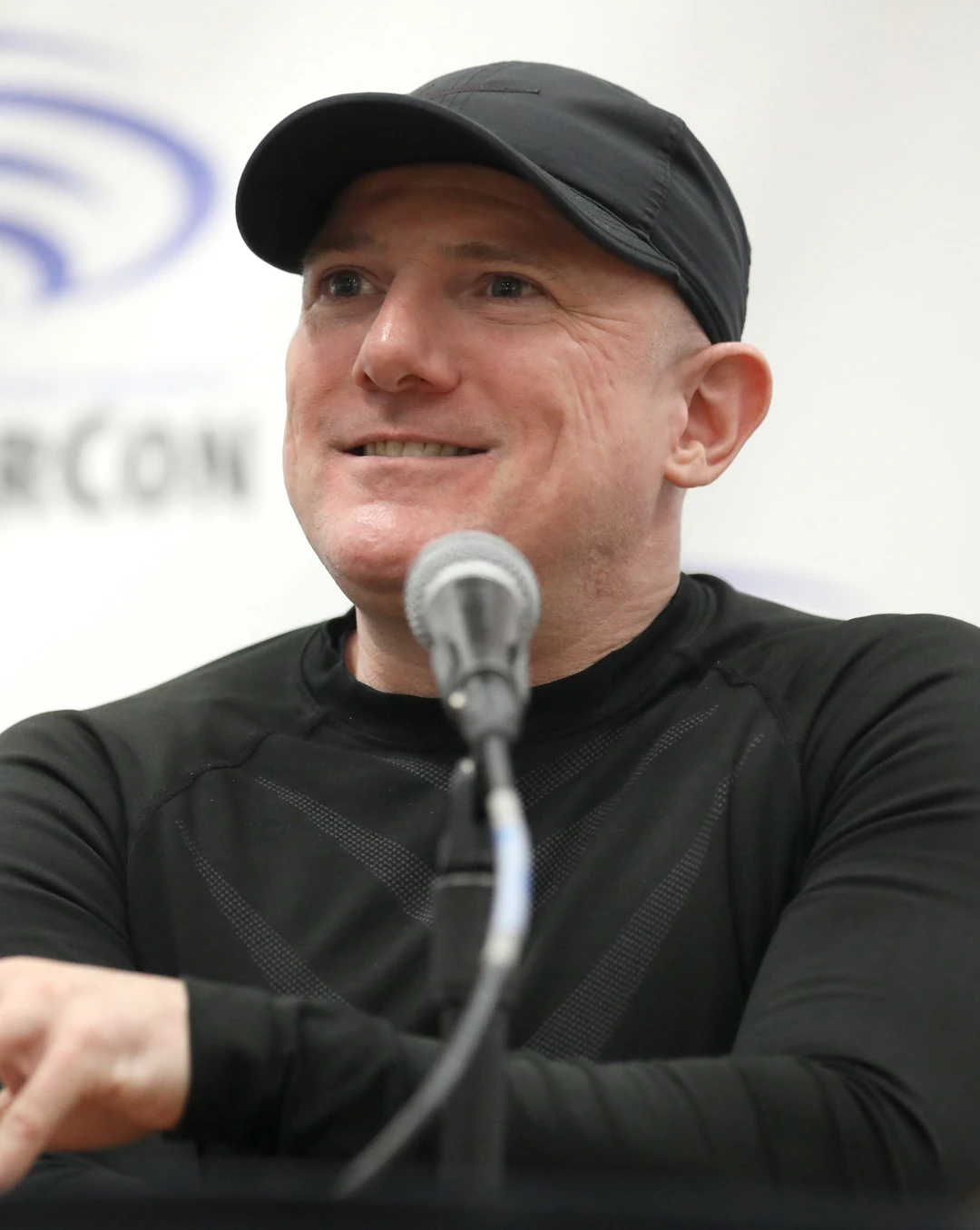 David Mack, a smiling man in a black cap, speaking into a microphone.