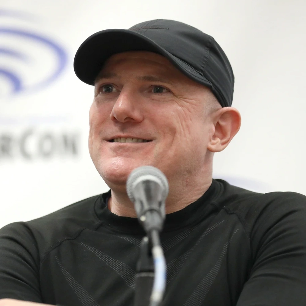David Mack, a smiling man in a black cap, speaking into a microphone.