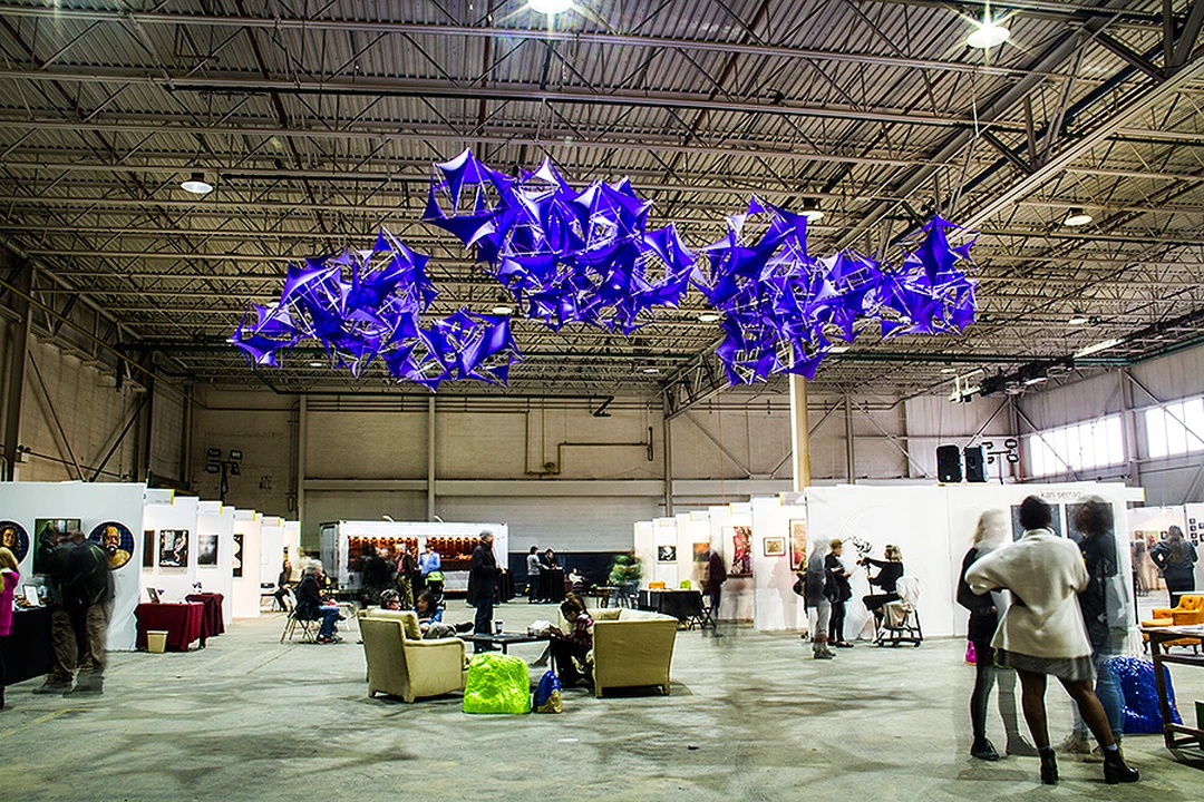 Interior of the ECHO Art Fair with a large purple hanging sculpture and visitors.