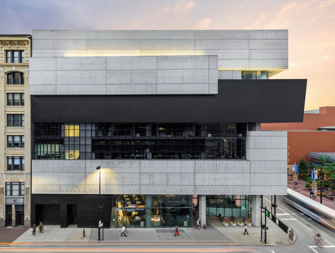 Photograph of the Contemporary Arts Center building in Cincinnati, the geometric concrete and black volumes designed by Zaha Hadid, with pedestrians on the sidewalk below.