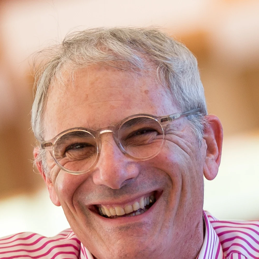 Portrait of Aaron Betsky smiling, wearing a pink-and-white striped shirt.