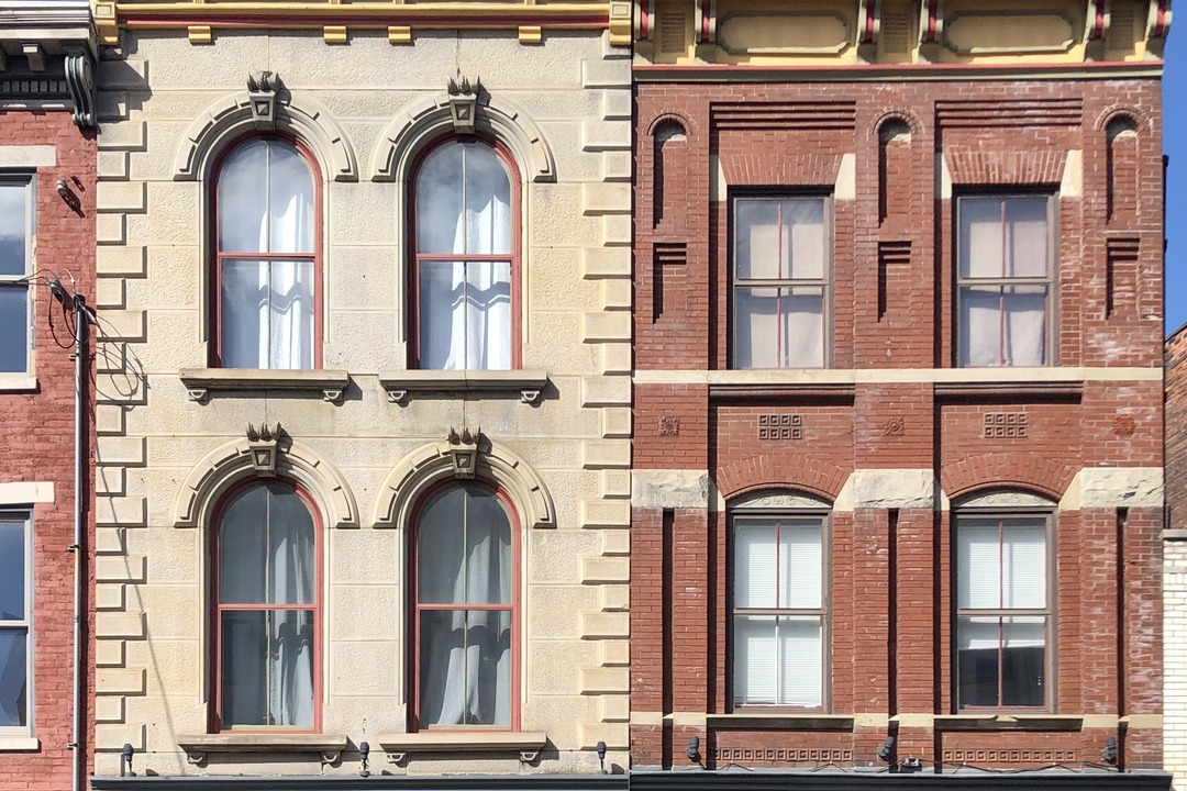 Historic brick and stone buildings with street-level storefronts on Pike Street in Covington, Kentucky