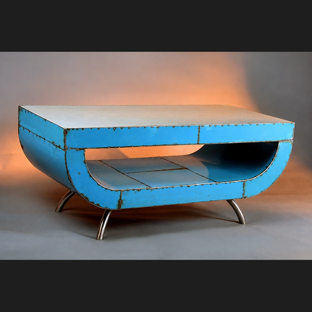Kevin Shahan, Lazy D Coffee Table: low coffee table of riveted reclaimed steel painted blue, with a rounded D-shaped open shelf and a pale top, on small curved metal legs.