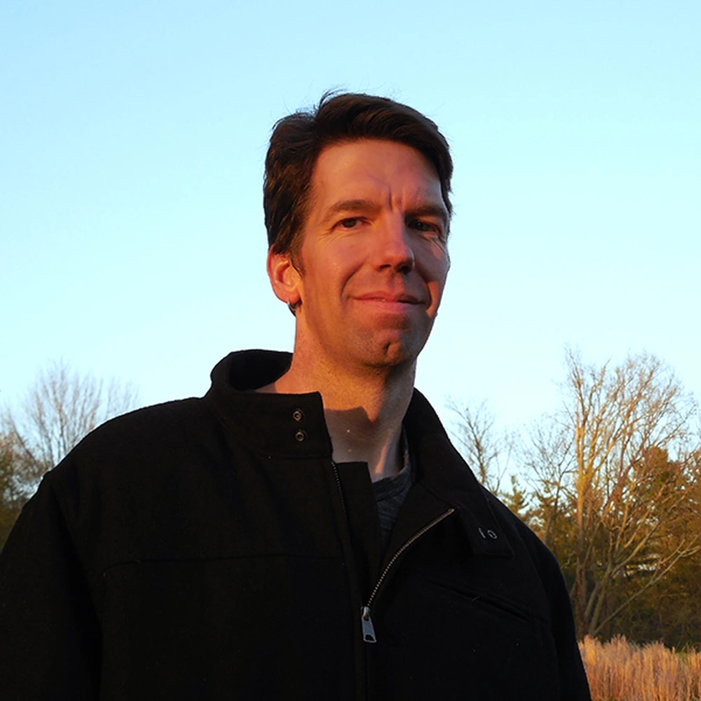 Portrait of Kevin Muente at sunset, outdoors in a dark jacket.