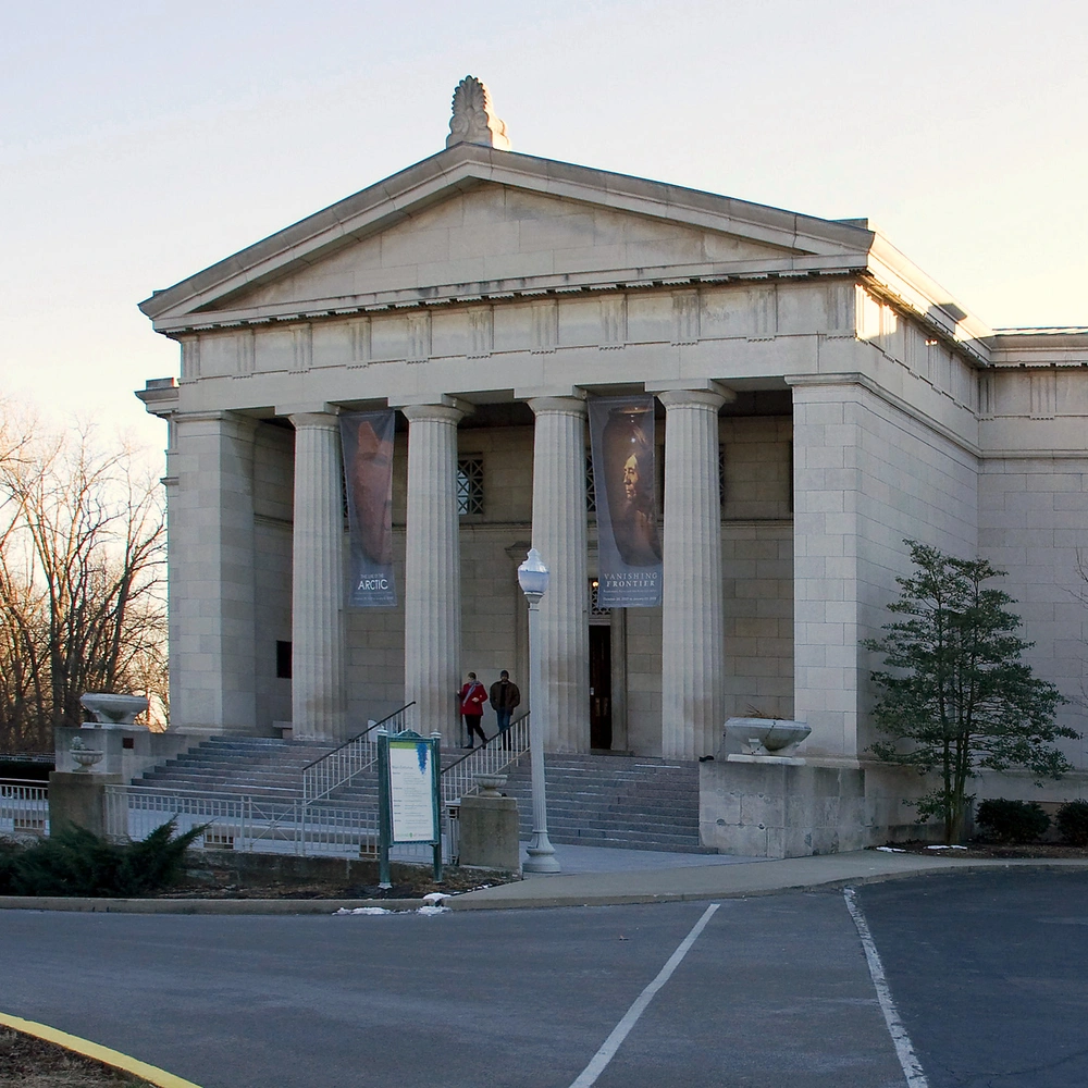 Exterior of the Cincinnati Art Museum: a stone neoclassical portico with columns on the left, a central facade and a tower behind, and a parking loop in the foreground.