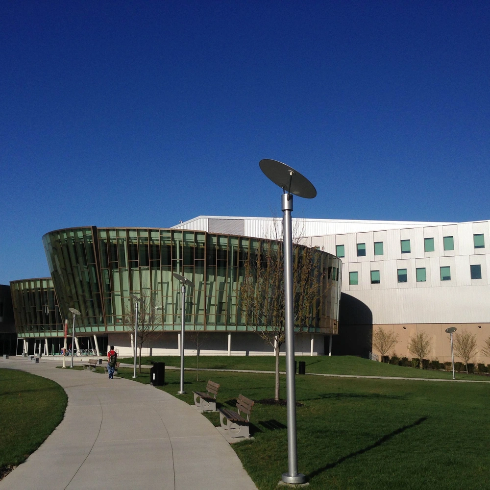 Exterior of Griffin Hall at Northern Kentucky University: a curved, glass-clad building beside a white block, on a sunny lawn.