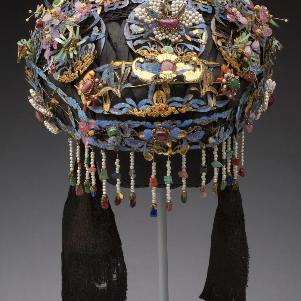 Wedding headdress of blue and gold cloisonne-like panels set with pink and green beads and stones, with pearl and bead fringe and dark silk side ties.