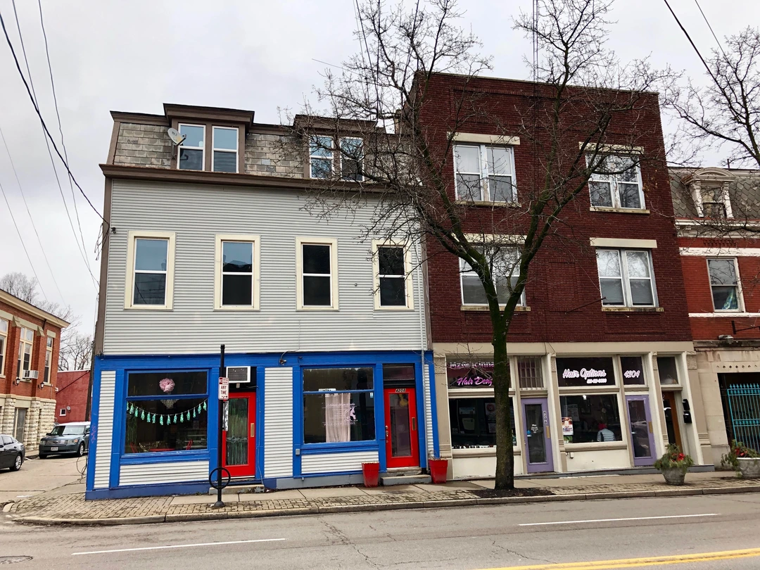 Row of two- and three-story storefronts along Hamilton Avenue in Northside, with a bare tree in front.
