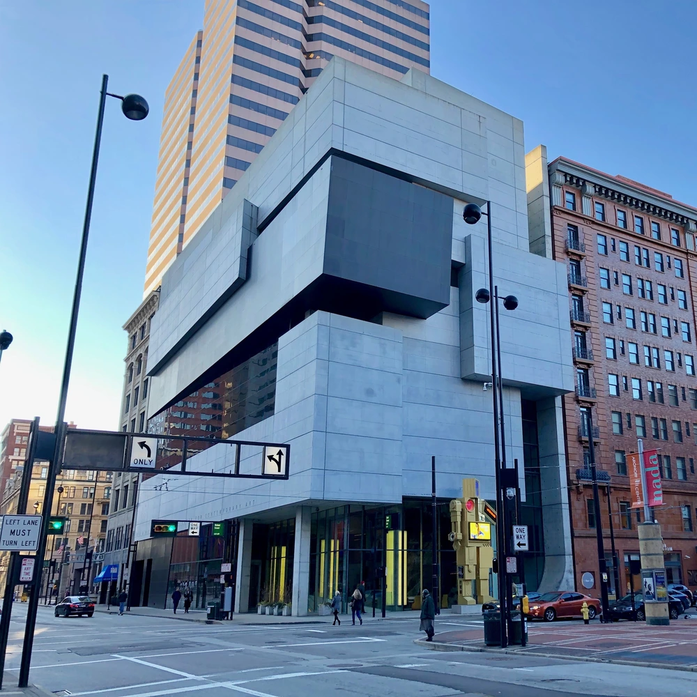 The Contemporary Arts Center in Cincinnati, a white stone building with a dark overhanging box, seen from the street under a blue sky.