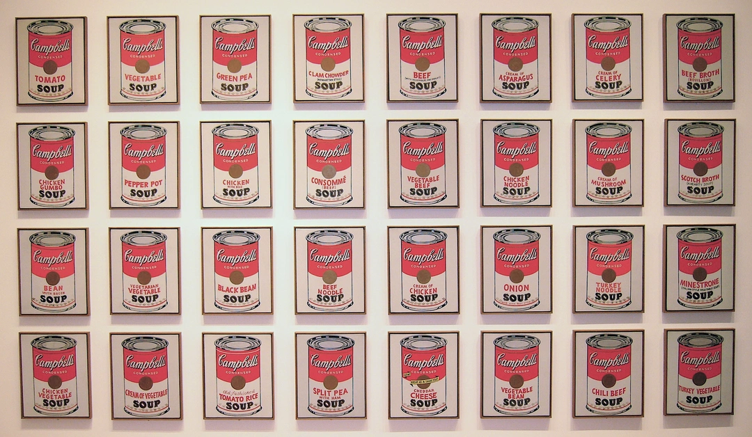 Four rows of eight framed Campbell’s soup can paintings hung on a pale gallery wall.