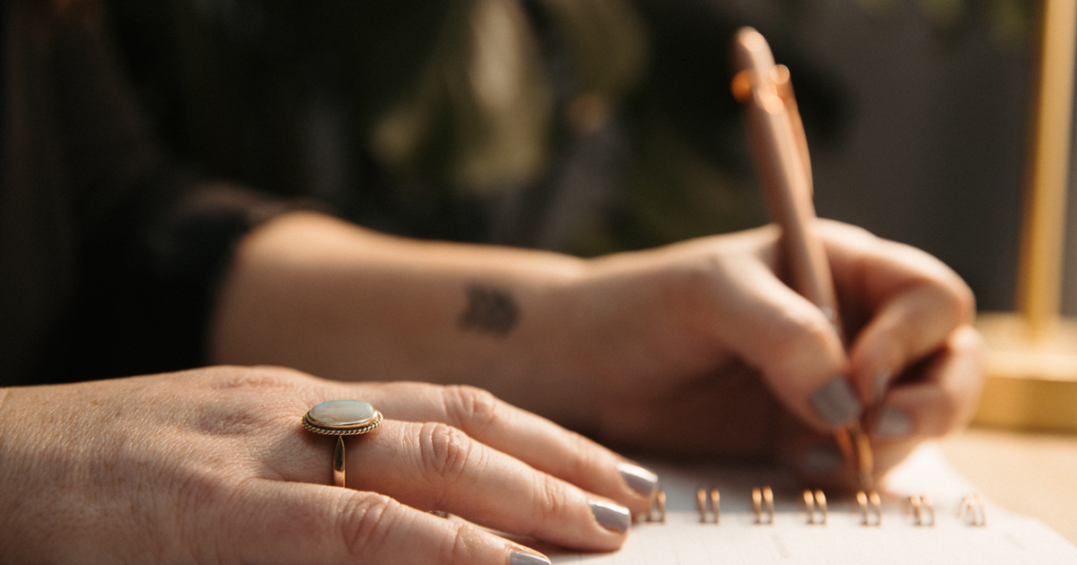 Abigail Grace Writing services header image, a left-handed woman writes with a pen about marketing content writing services