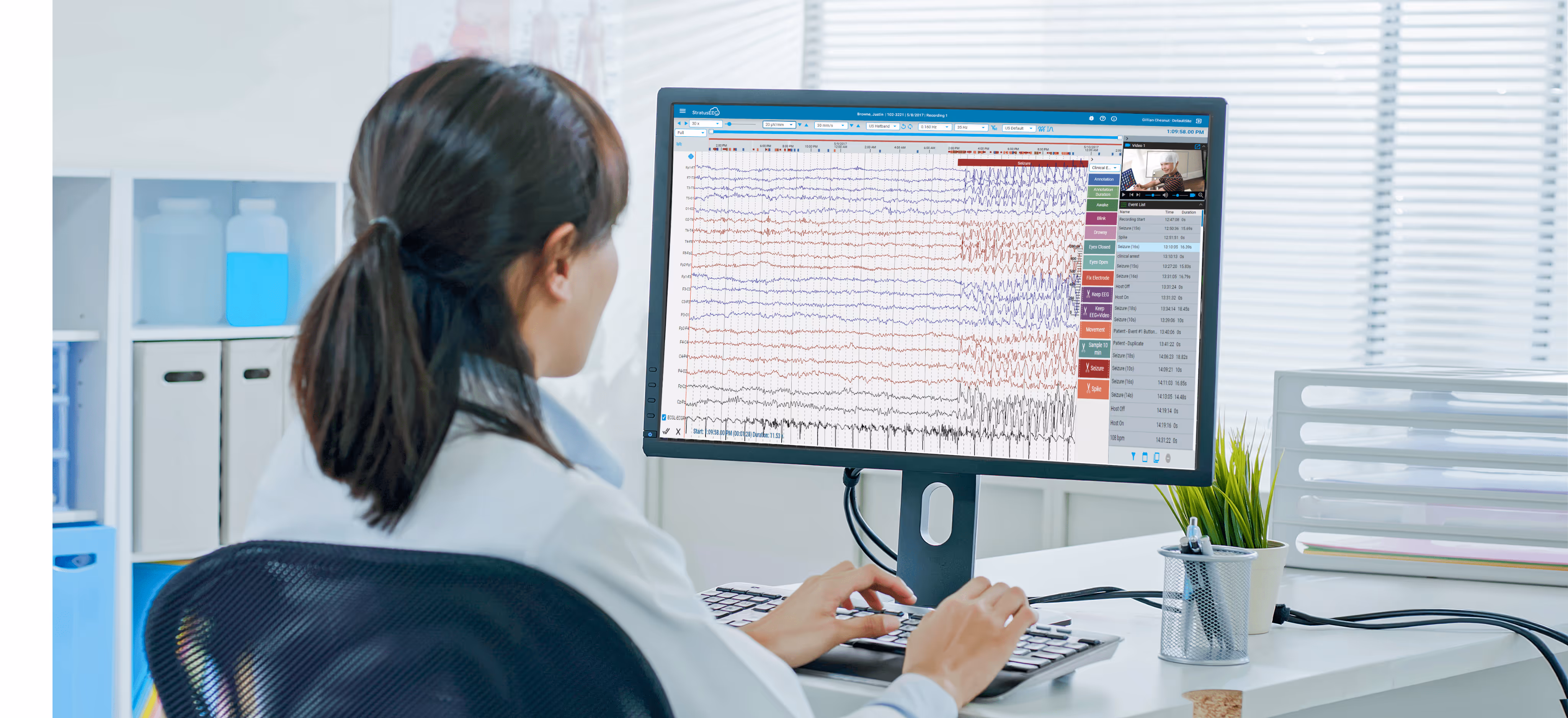 Medical professional analyzing EEG data on a computer monitor in a bright office.