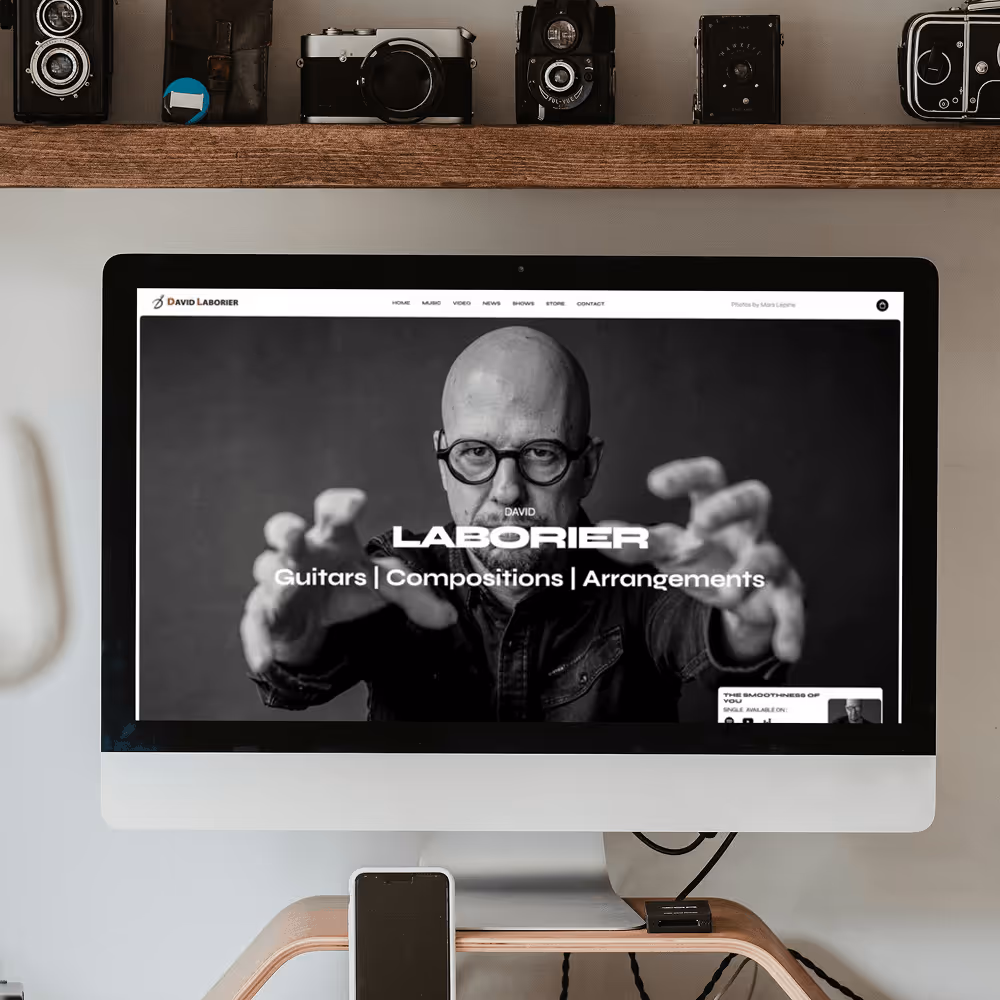 Desktop computer screen showing a black-and-white homepage of David Laborier featuring his portrait and text: 'Guitars | Compositions | Arrangements'.