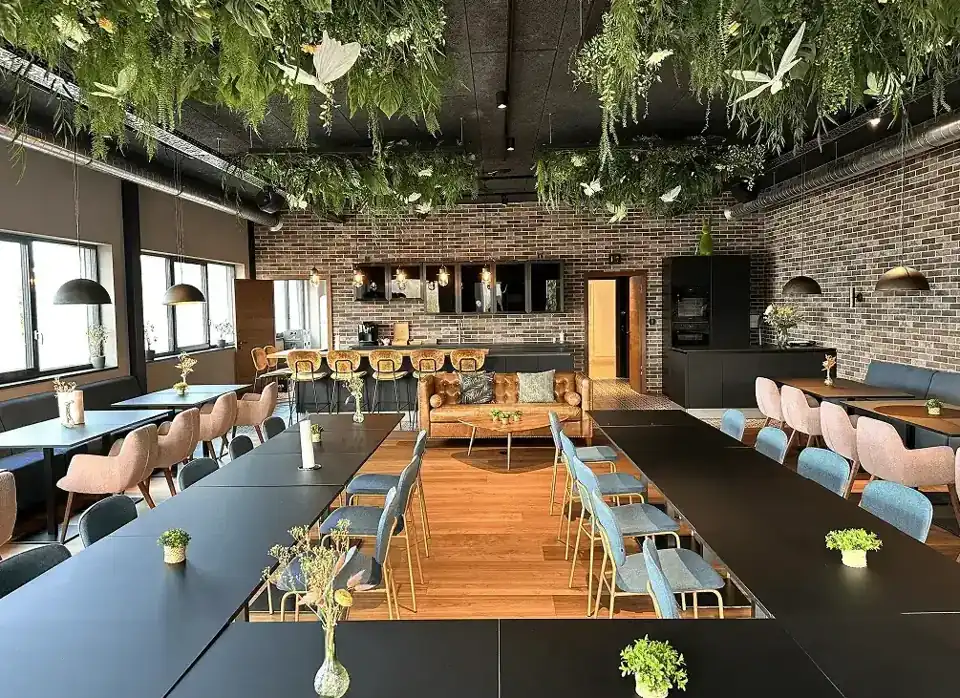 Our office in Mertzig: meeting room with black tables, blue and pink chairs, brick walls and hanging greenery