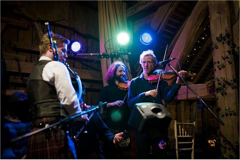 Oxford ceilidh band leading traditional dances inside a historic college hall.