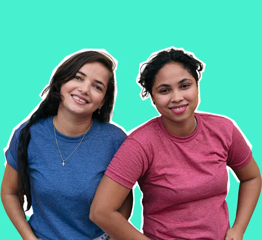 Two smiling women standing close together against a teal background, one wearing a blue shirt and the other a red shirt.