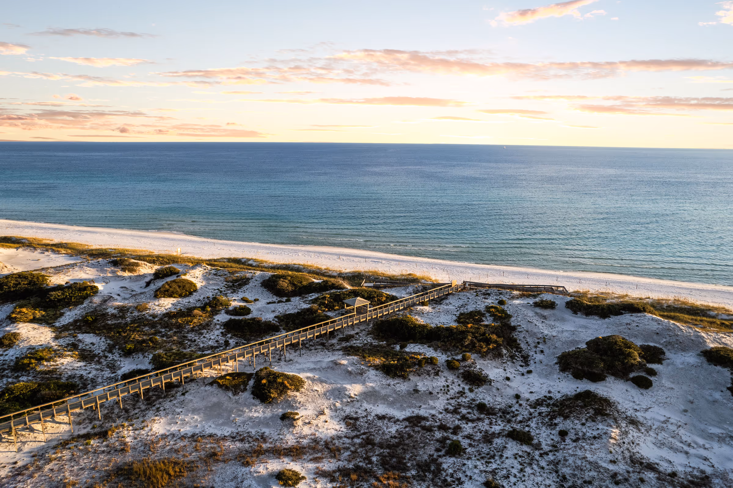 Golden hour aerial of Florida Gulf Coast beach with boardwalk over dunes