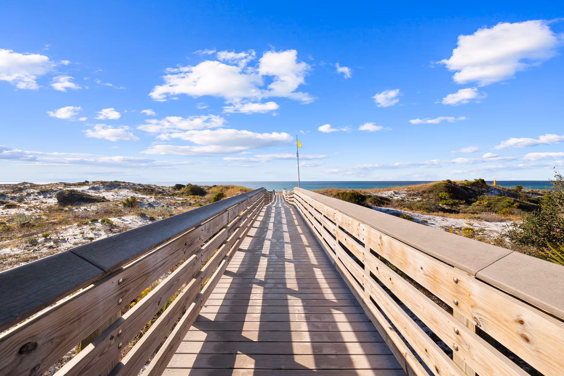 Florida beach access walkway with wooden railings and turquoise water view