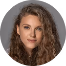 Frau mit lockigem Haar und grauem Hintergrund.