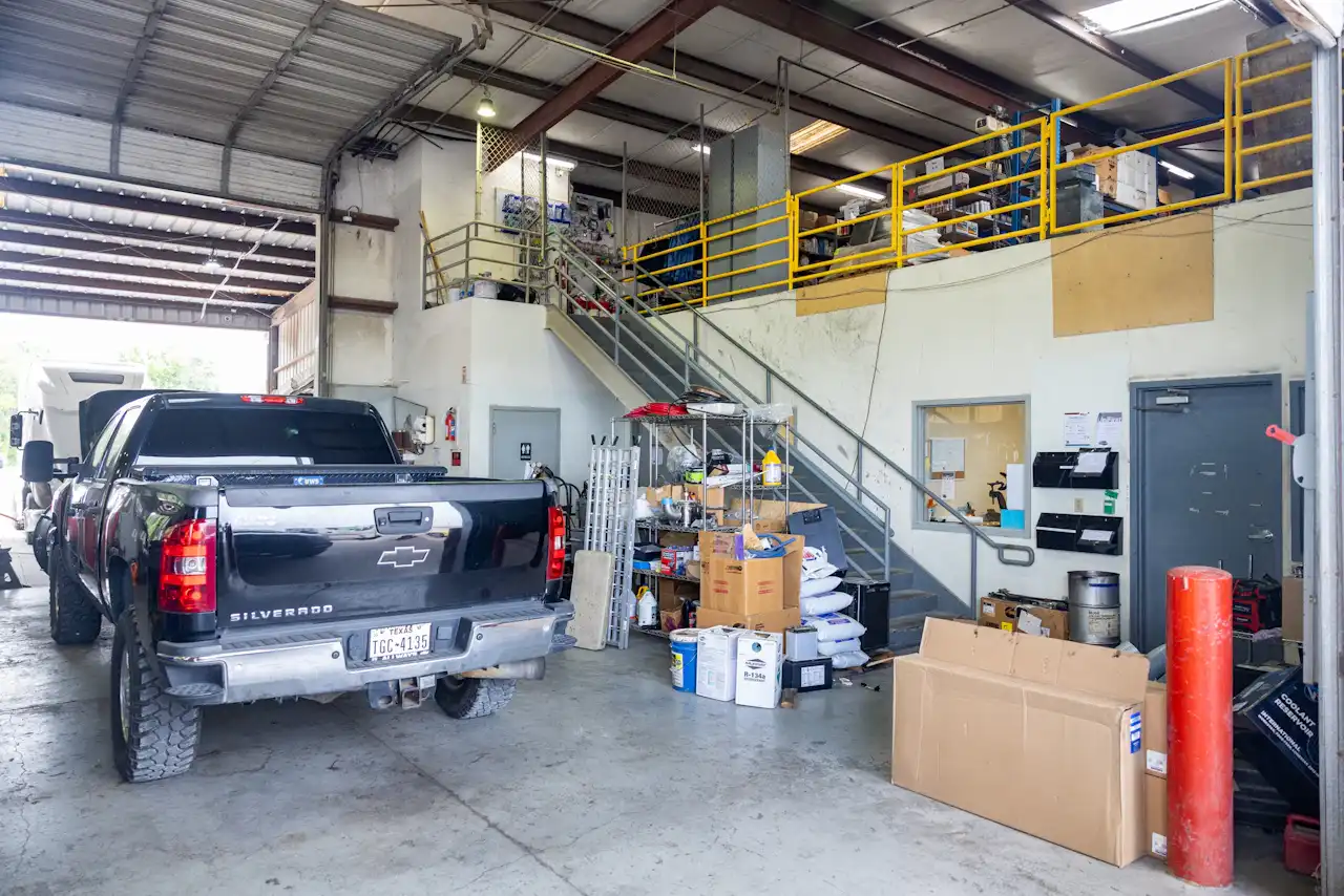 Heavy-duty repair shop interior with service office, parts storage, and a service truck parked inside the maintenance facility.