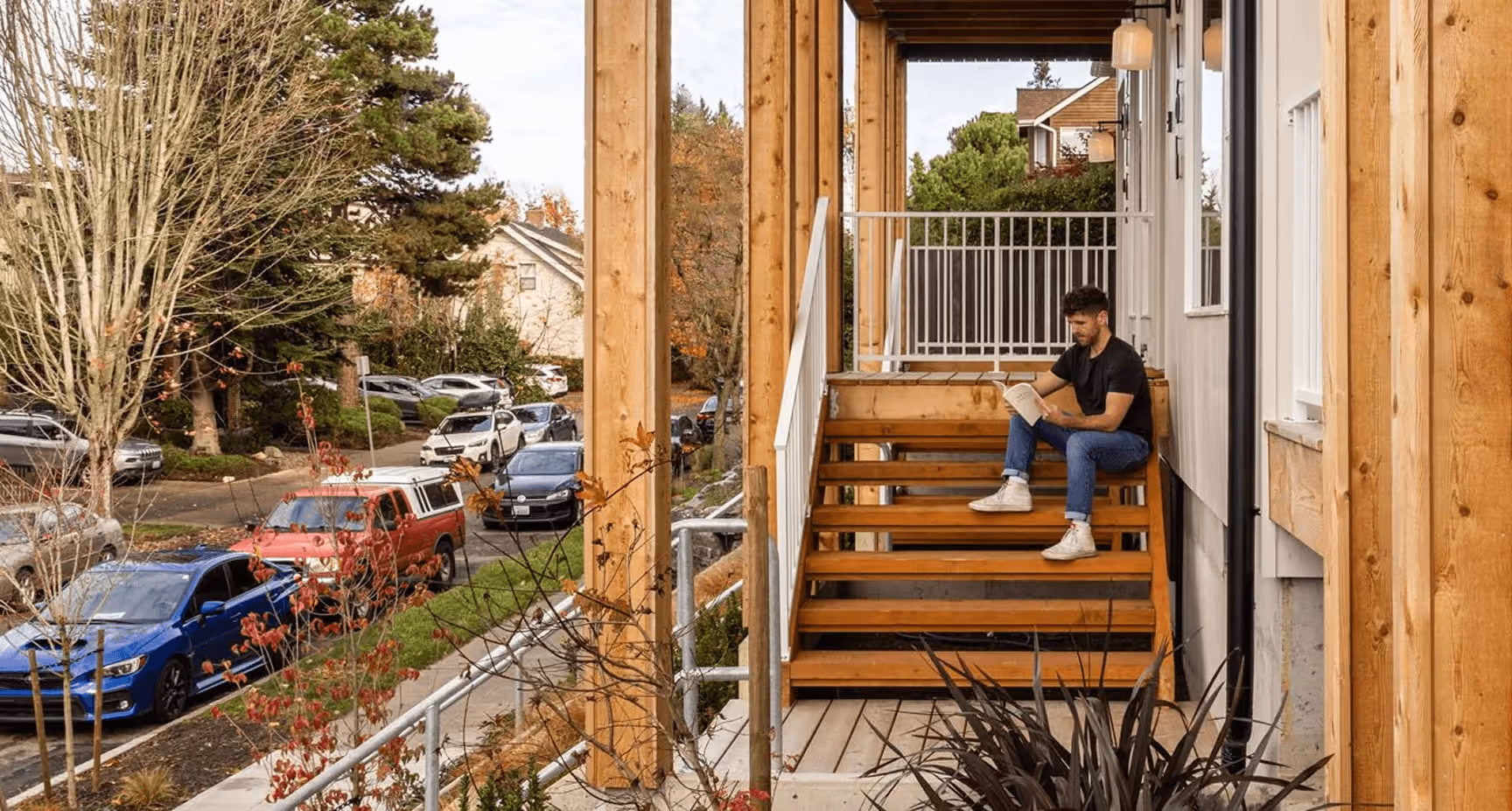 A man sitting on a wooden staircase reading a book.