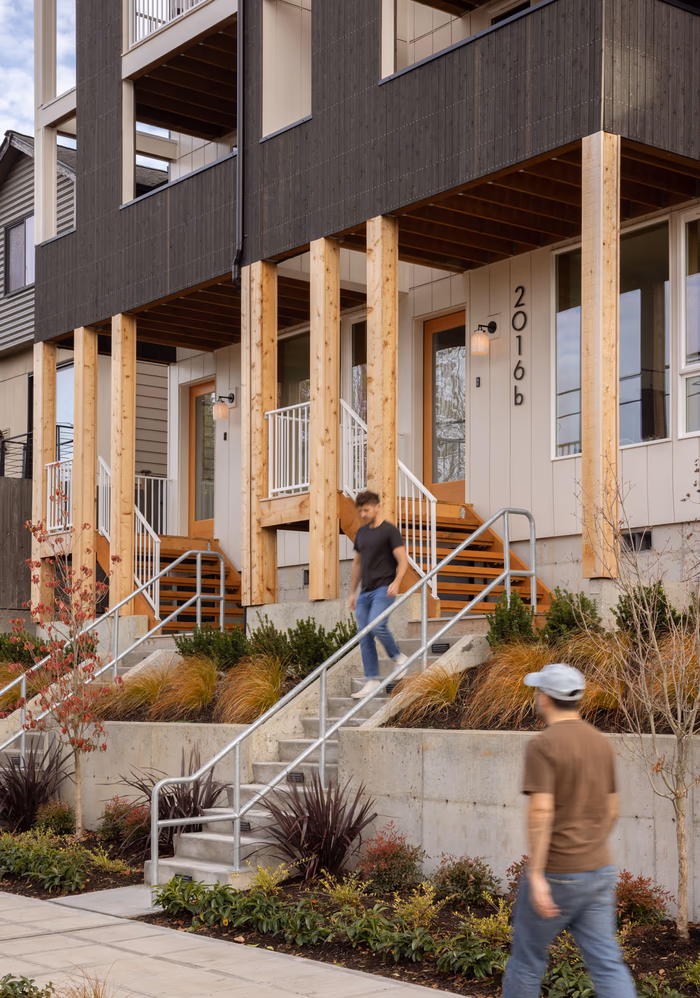 Front door of a townhome with 2 flights of stairs and two men walking 