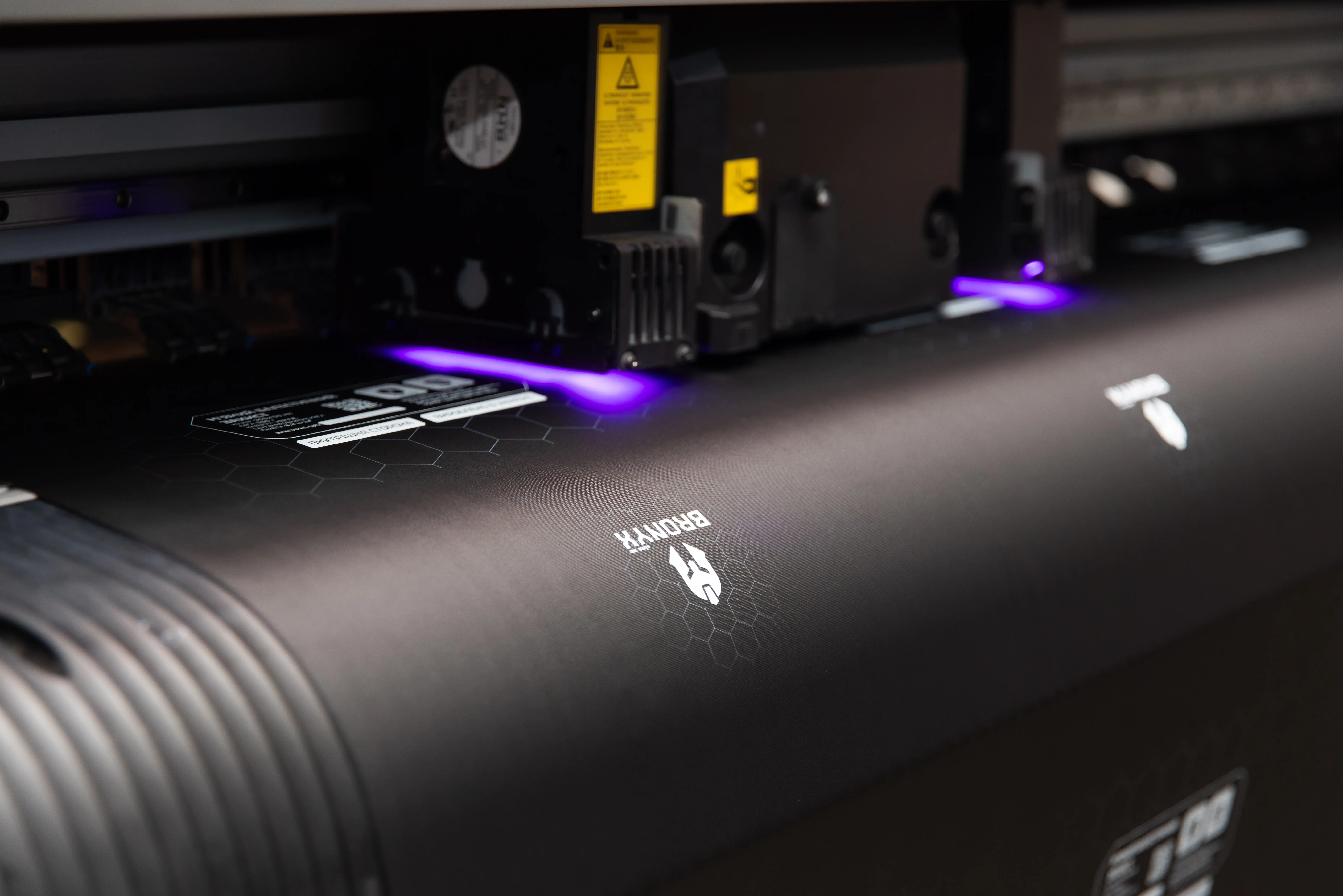 Друкуючий блок промислового принтера з фіолетовим світлом і напечатаним логотипом BRONYX на чорній поверхні.