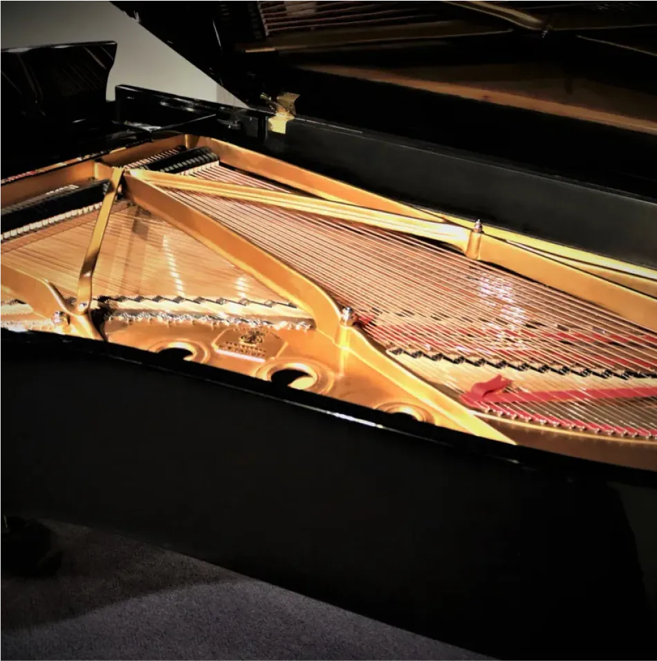 Close-up of a Certified Steinway grand piano's open lid reveals the intricate strings, hammers, and soundboard within its polished black frame.