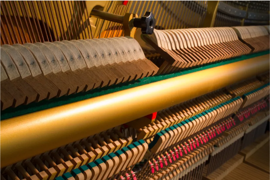 Close-up of a piano's internal mechanism, showcasing the hammers, strings, and dampers in wooden and metal components. Perfectly capturing the intricacies involved in tuning and potential repairs to ensure harmonious melodies.