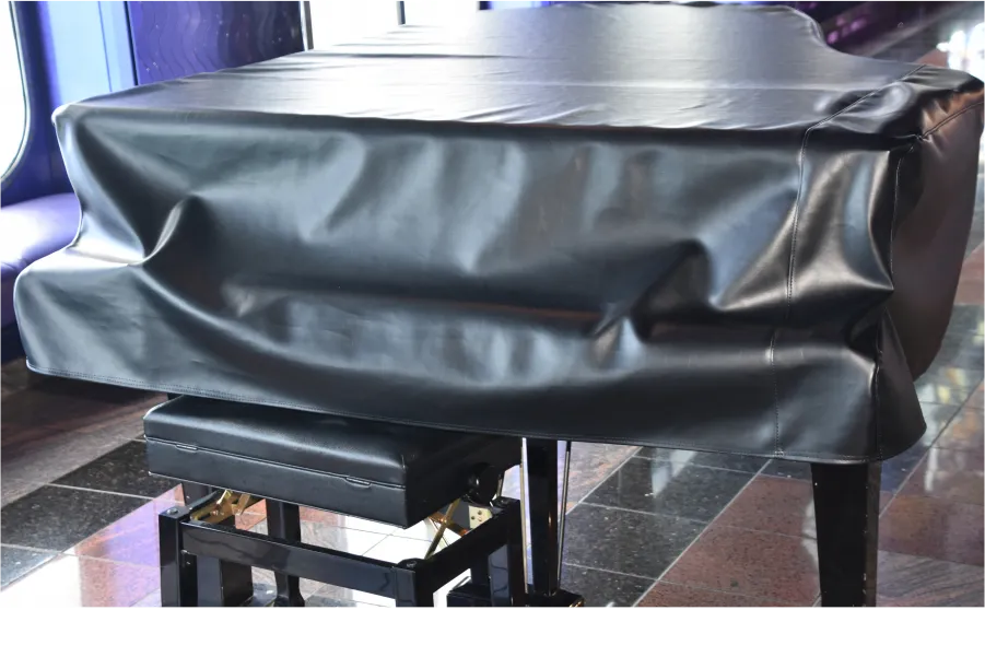 A black grand piano, enveloped in a fitted cover and concert-ready for any occasion.