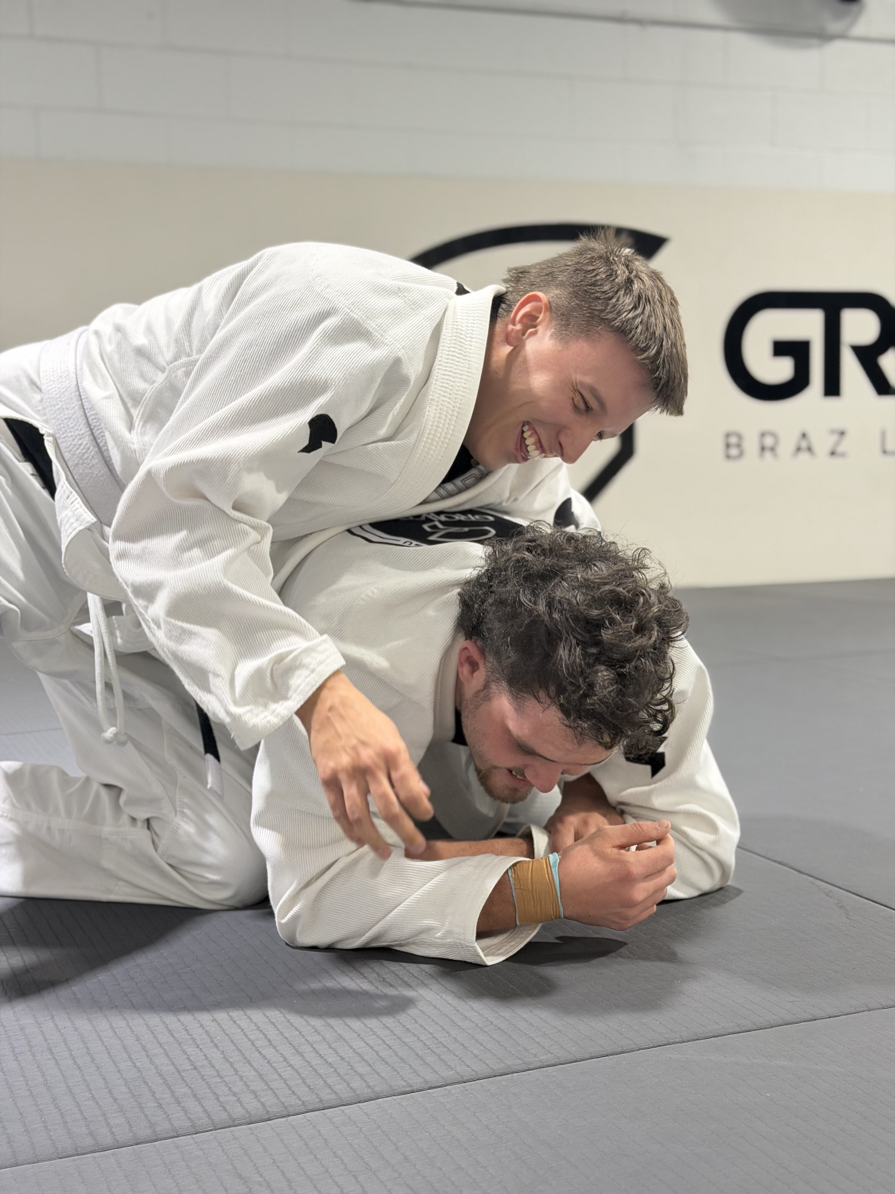 Black belt coach demonstrating ground technique in Gi at Growth BJJ