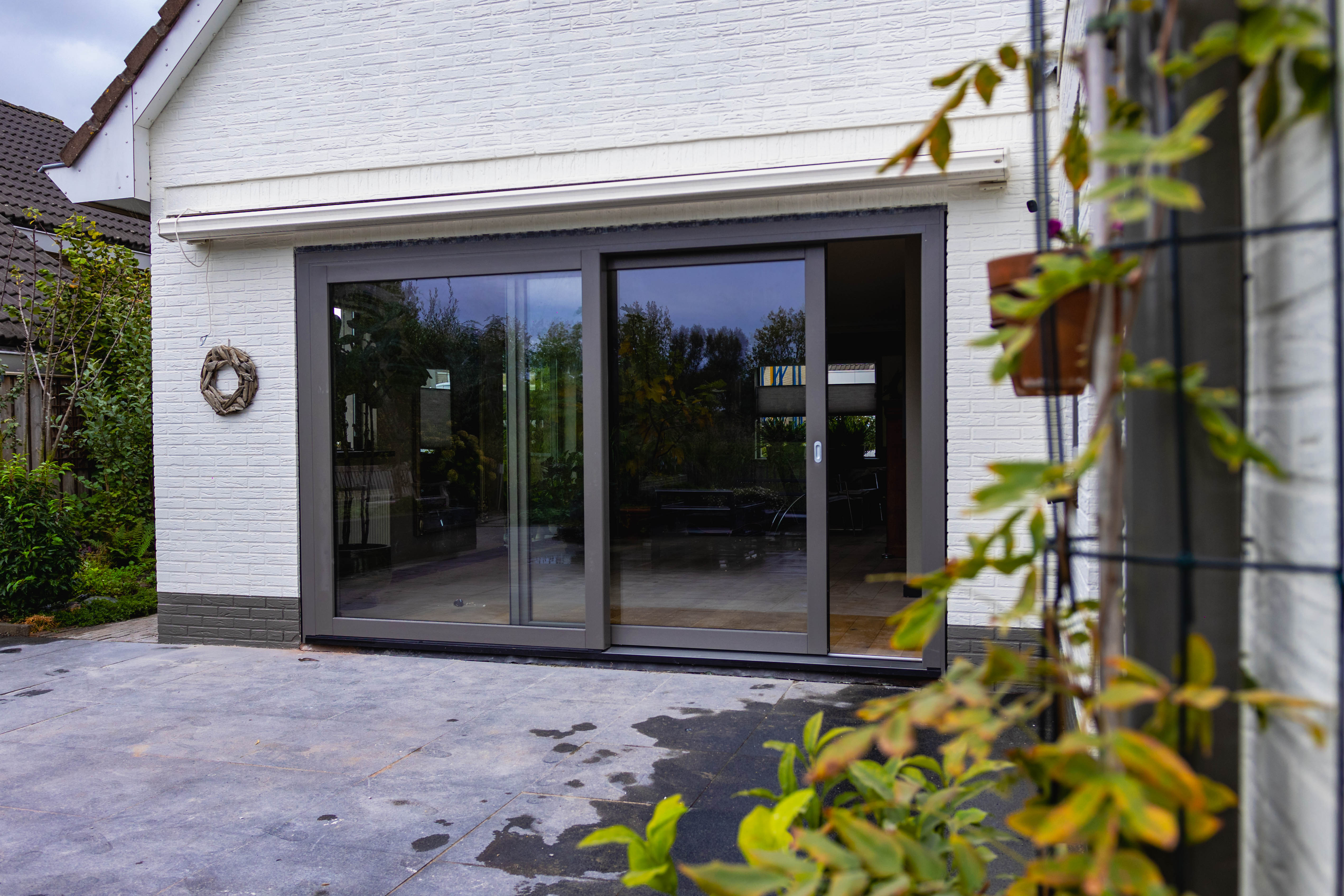 Antraciet schuifpui met groot glasoppervlak aan de tuinzijde van een woning